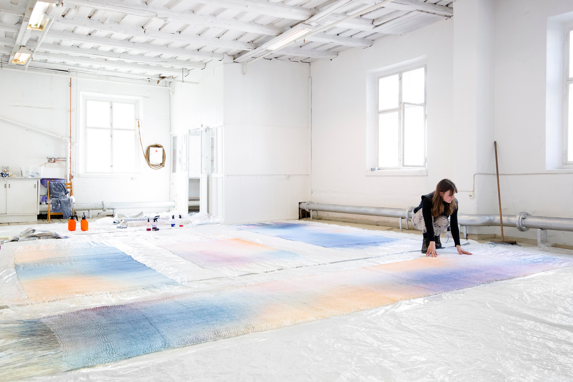 Aurora Passero i atelieret, med tekstiler i blått, lilla og gult spredt ut over gulvet.