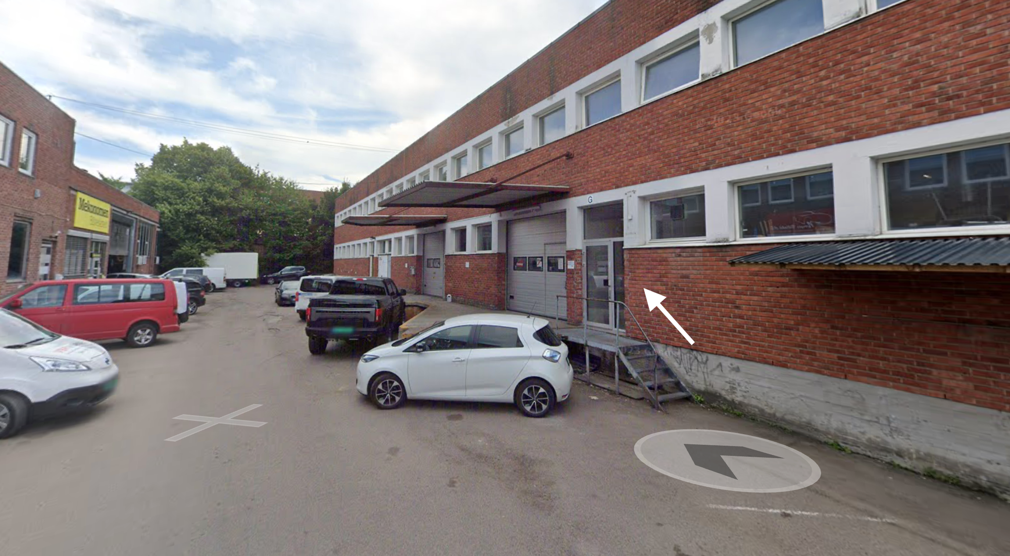Screenshot av google streetview med to lave industrielle mursteinsbygg med biler parkert mellom