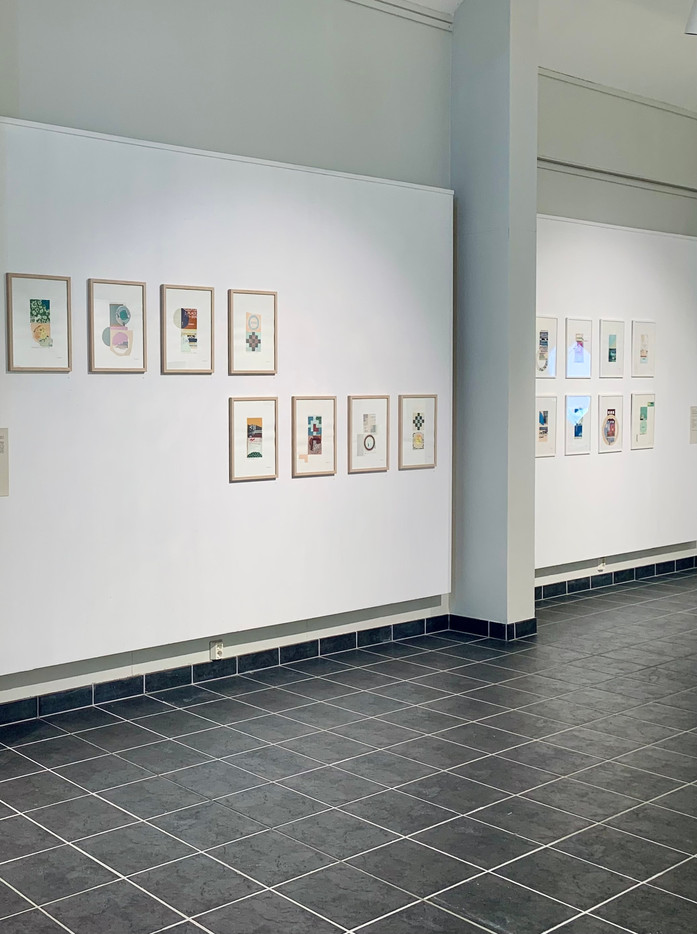 Stort galleri-rom med en serie innrammede collager i samme størrelse montert på vegg i 2 grupper