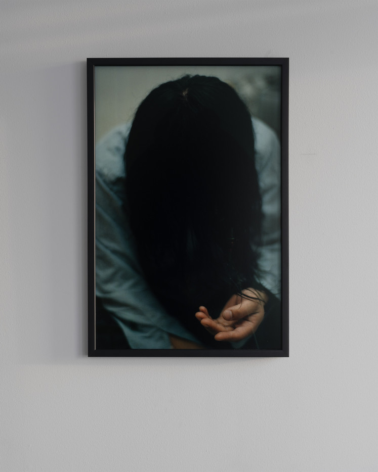 A hand stretches itself forward from flowing black hair.
