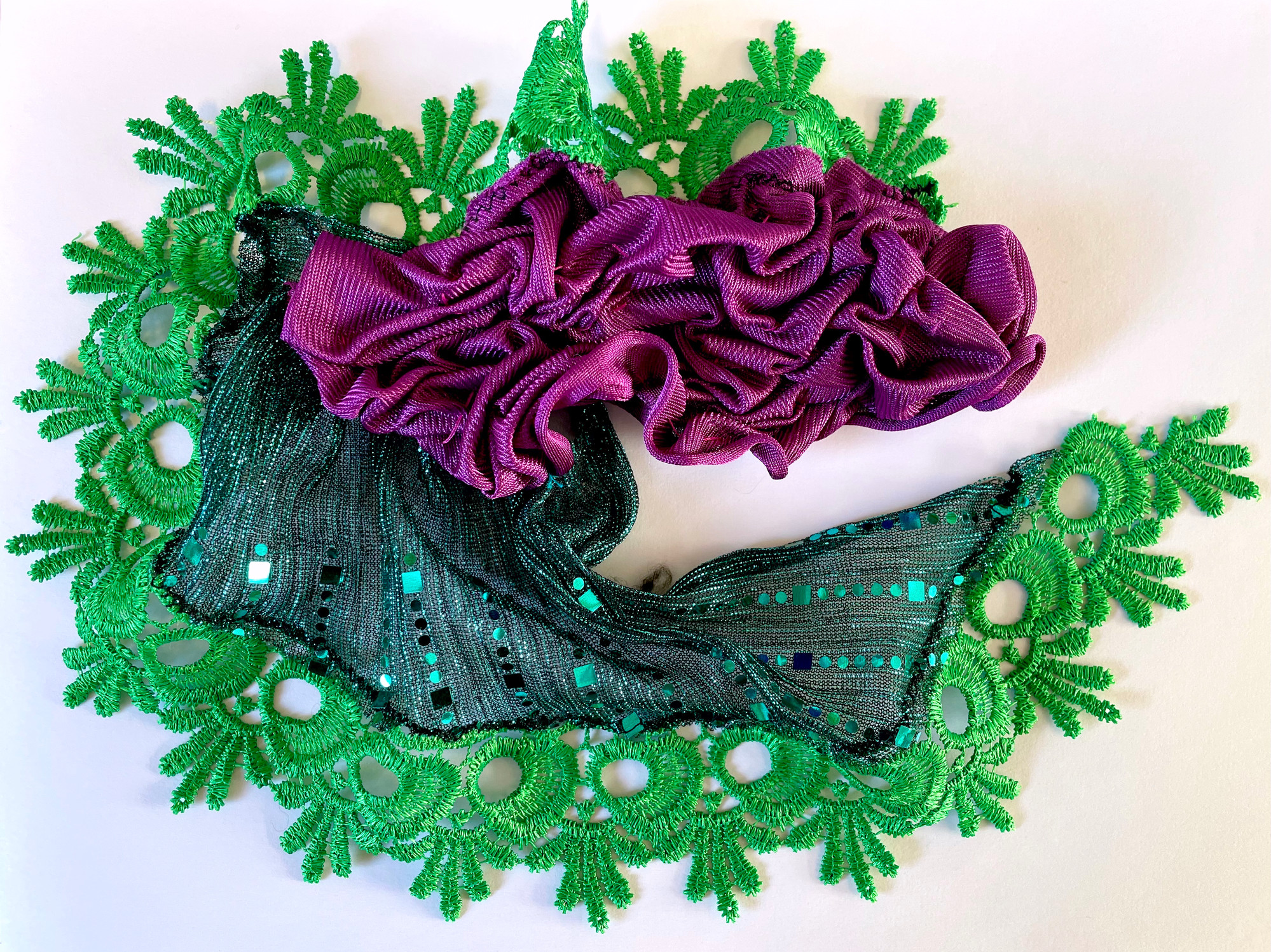 Close up of an art work made with three different types of fabric in green and lilac. The lilac fabric is ruched.