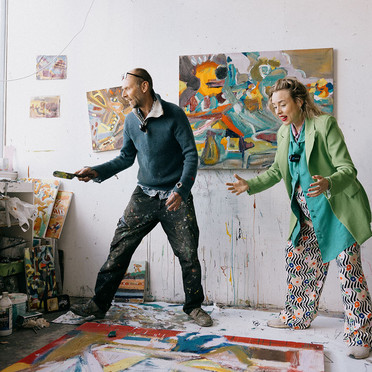 Artist Jens Hamran and reporter Ragnhild Brochmann leans over a canvas on the floor. Paint stains, clutter and paintings in rich colours fills the space.