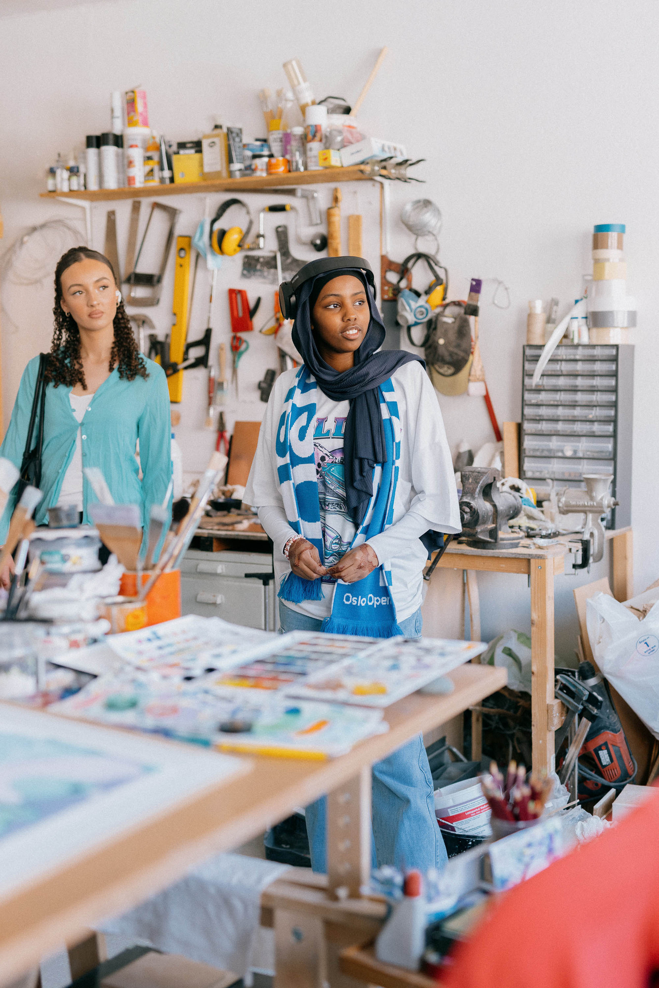 To unge kvinner ved et arbeidsbord med maleutstyr.