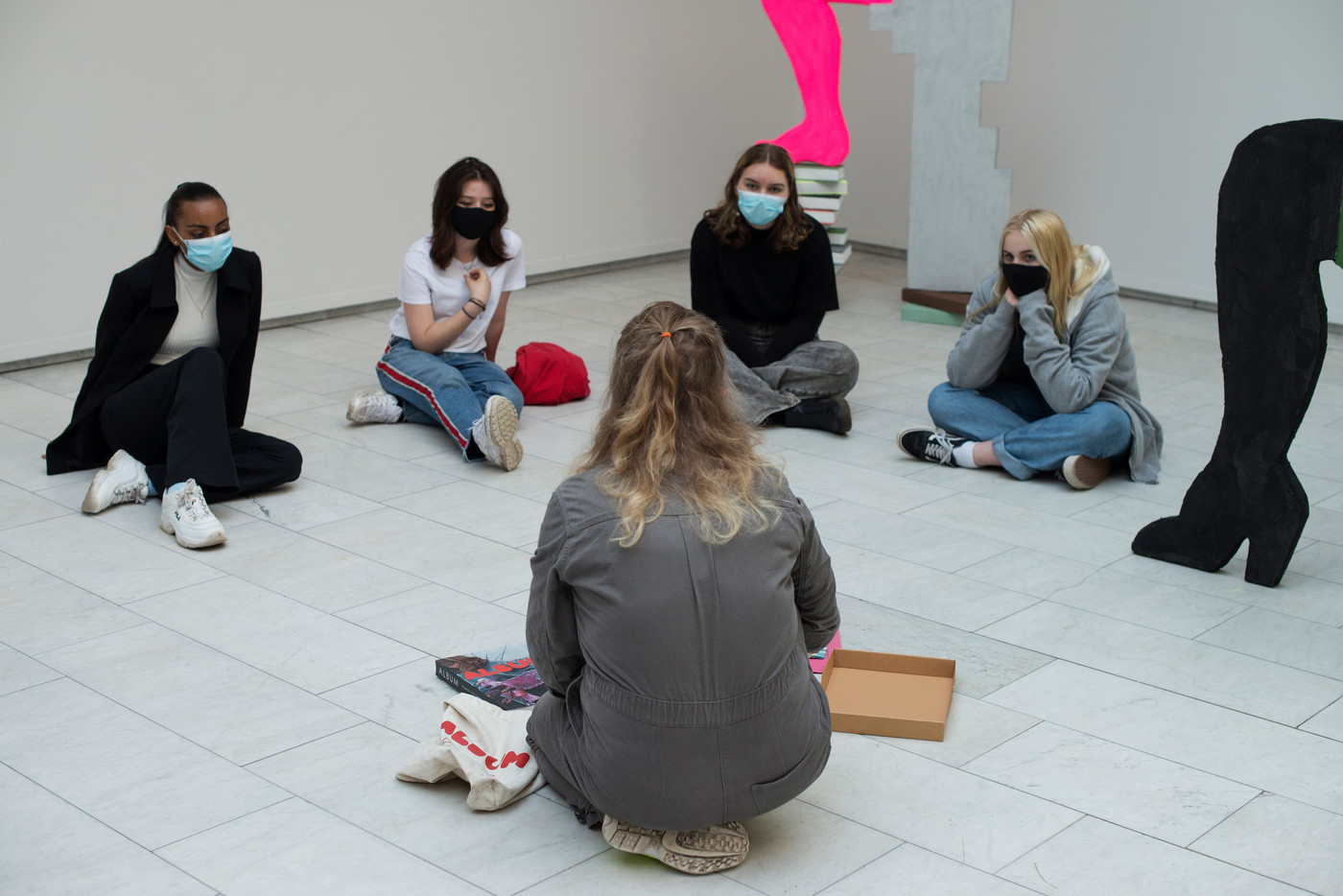 Fire unge jenter sitter foran kunstner Elise Storsveen. 