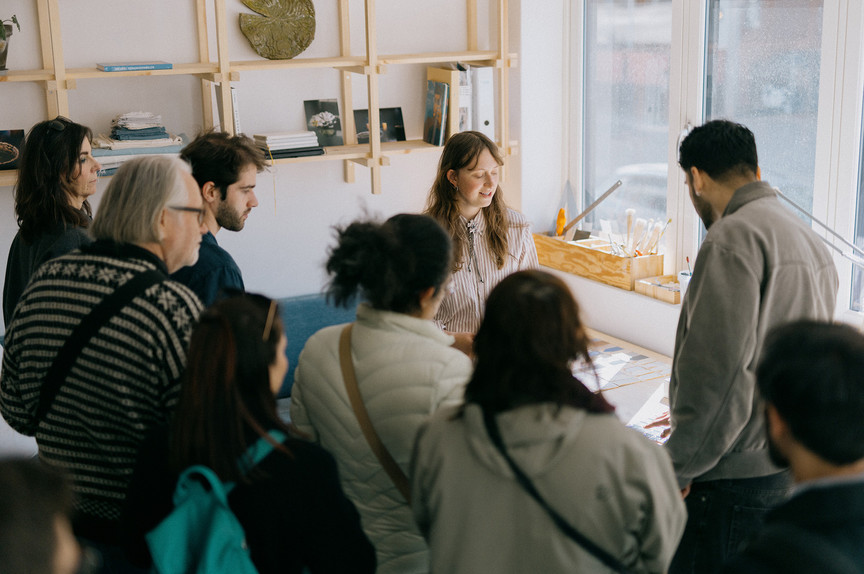 The artist, a young woman, surrounded by curious visitors.
