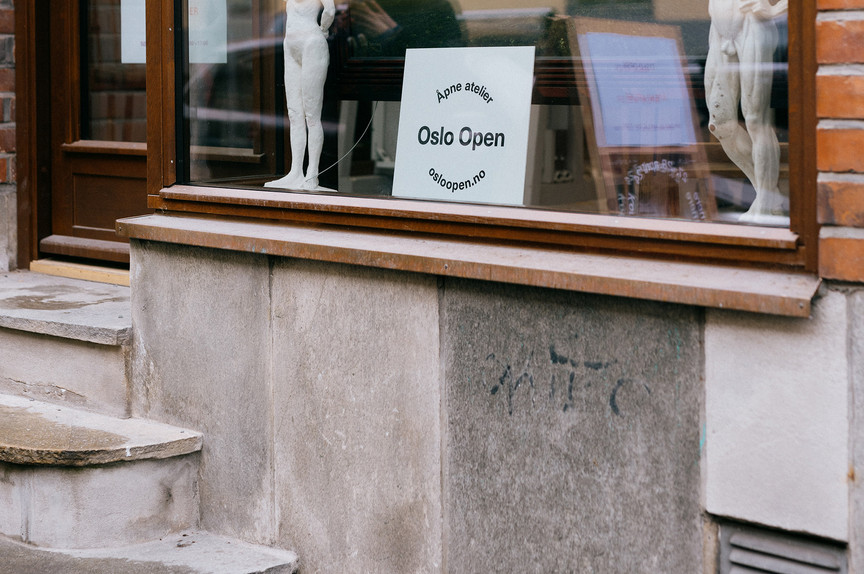 A staircase to a studio. In the window, a sign reads: Oslo Open.