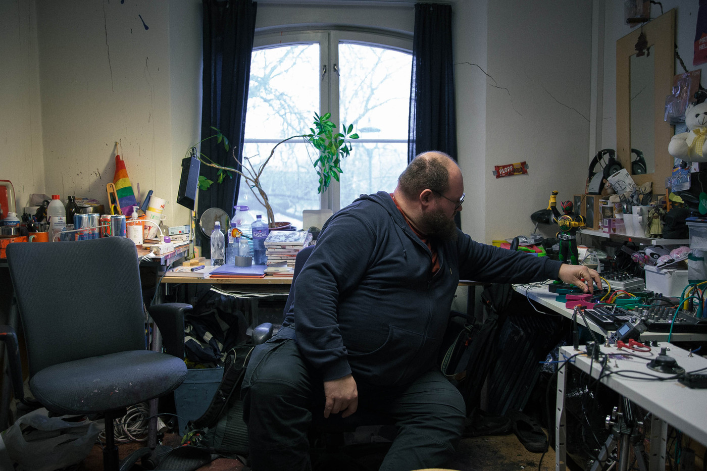 En kunstner sitter ved skrivebordet og vrir på knotter.