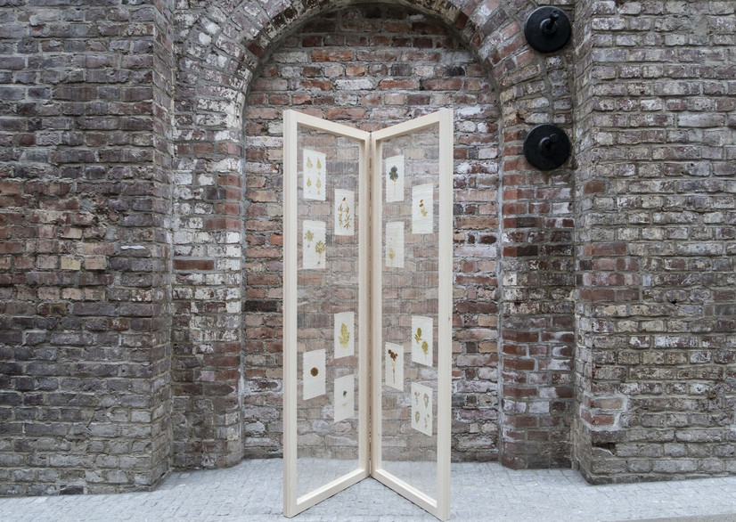 Verket Herbarium består av to avlange rammer i lyst tre som henger sammen med to hengsler. Verket står som en åpnet bok i rommet. De er 180 cm lang og 60 cm brede. Rammene fungerer som en billed-vev, og en lys beige lin-renning er spent opp i dem. Hvit silke med plantetrykk er klippet opp i strimler og vevd i firkanter i A5 format, seks plante-trykk er vevd i hver ramme.