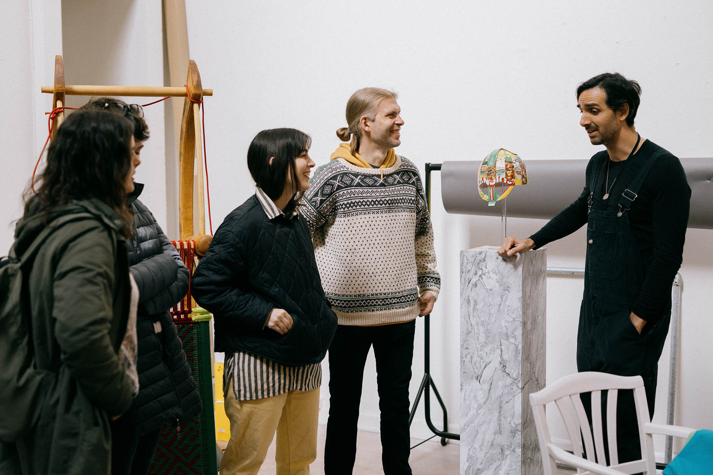 Fire personer smiler mens kunstner Sayed Sattar Hasan forteller. Mellom dem står en tolkning av en vikinghjelm på en pidestall.