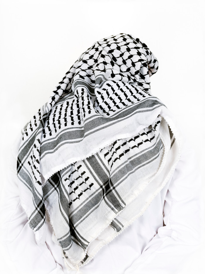 Bildet viser en palestinsk mann i hvit skjorte og keffiyeh sett bakfra.